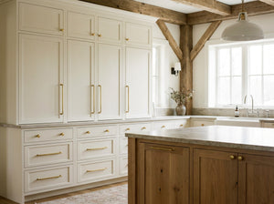 Modern kitchen with white cabinets, wooden island, and natural light.